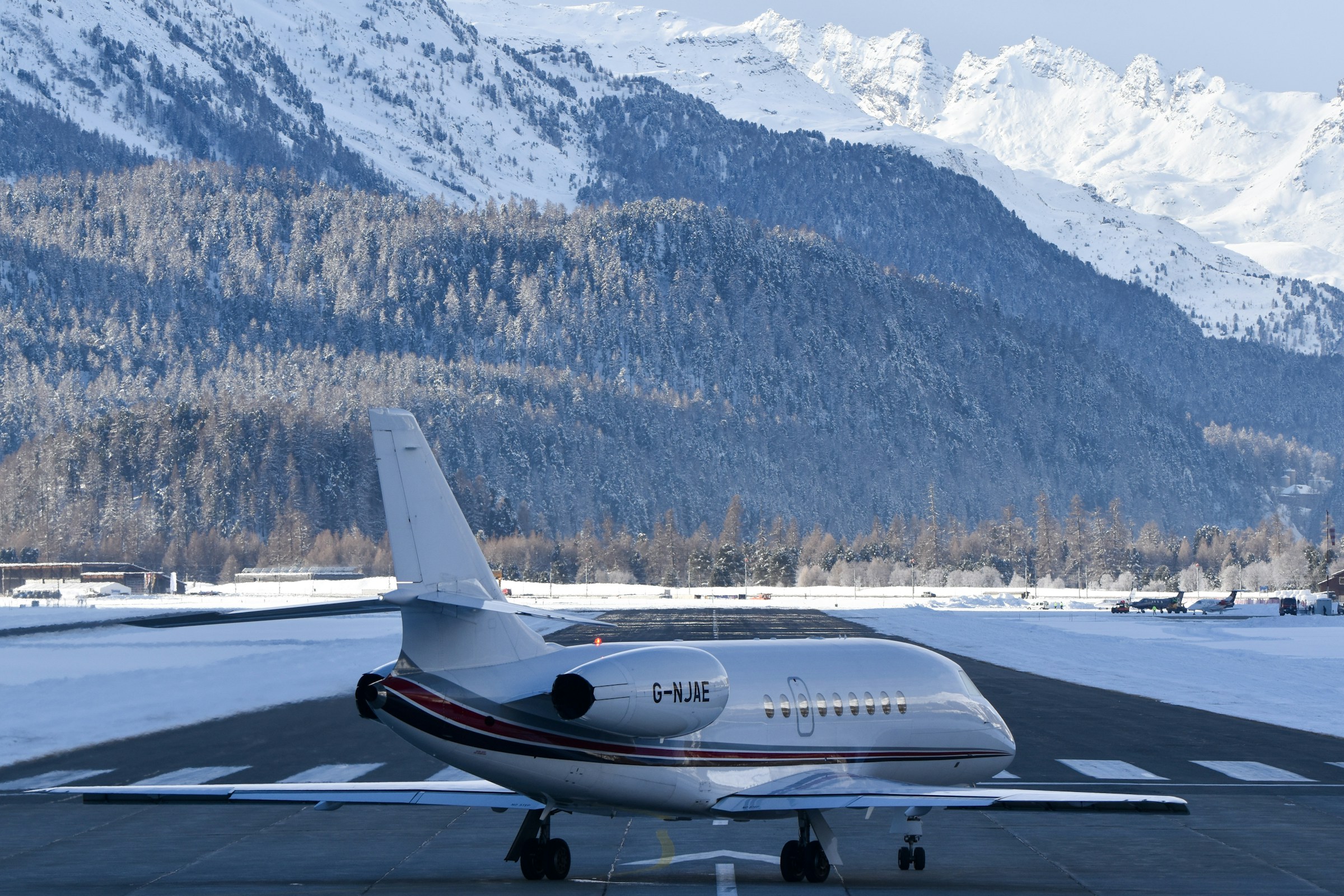 Private jet on a snowy runway with mountains behind it
